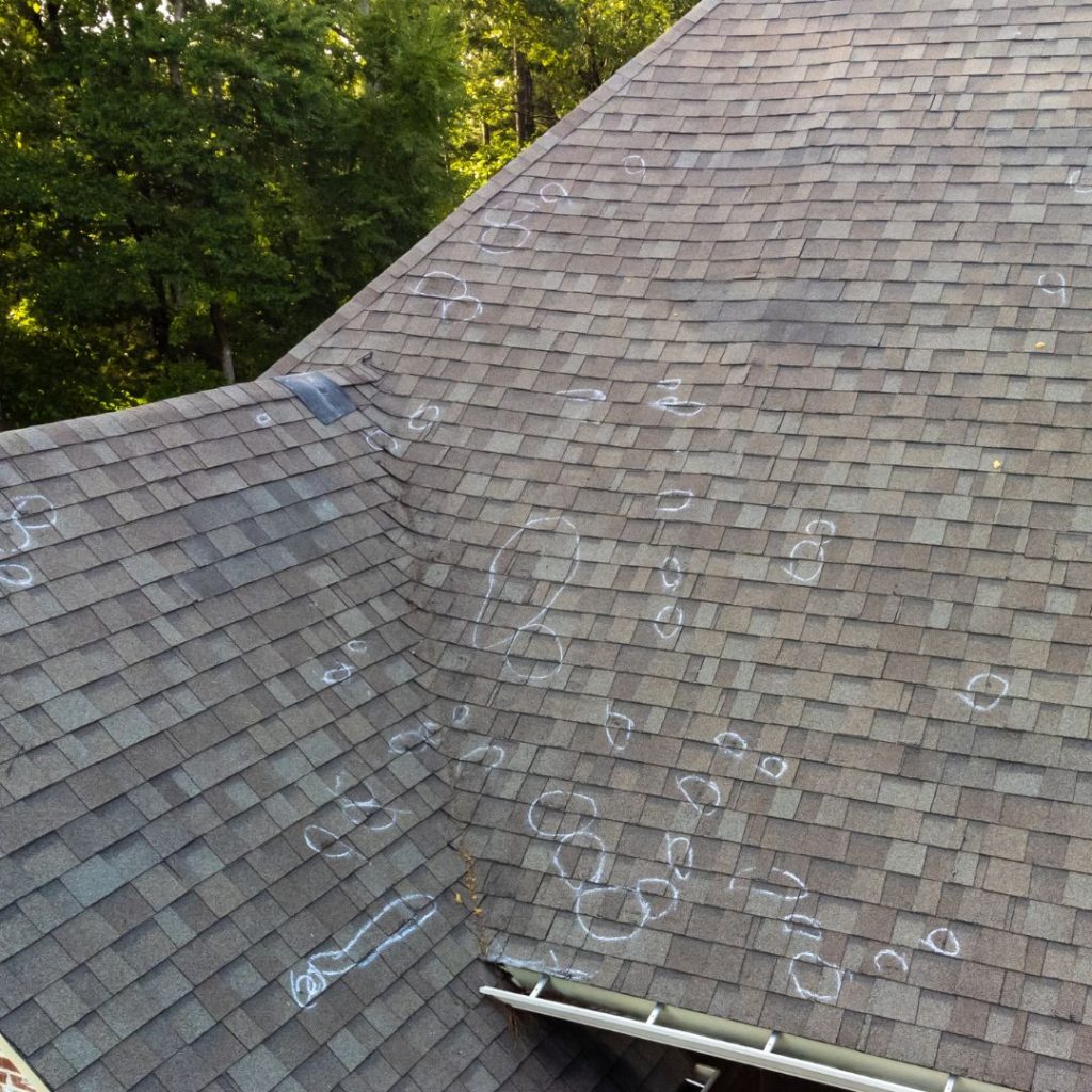 asphalt roof with hail damage spots circled with chalk