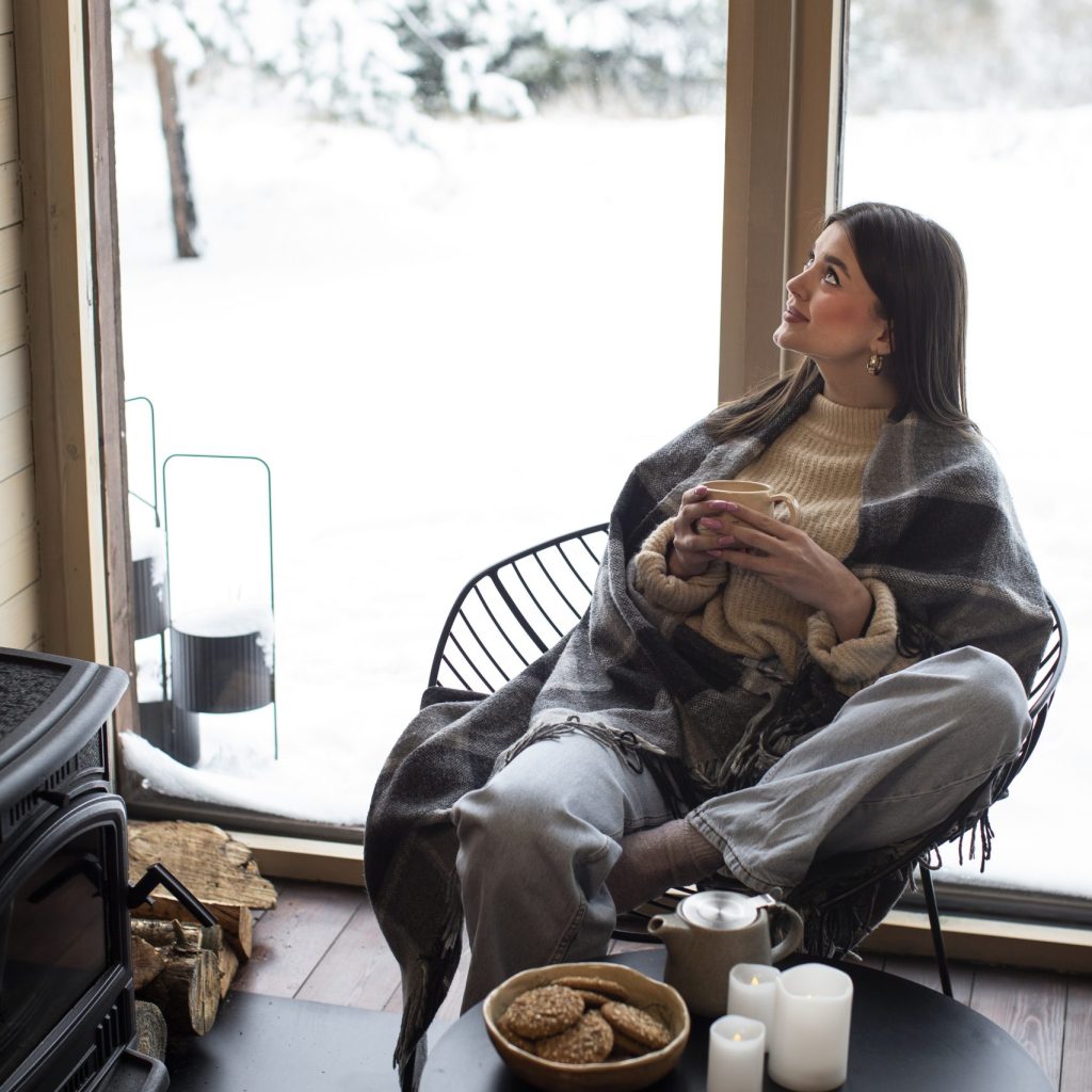 woman sitting inside appreciating insulated windows while snow is outside